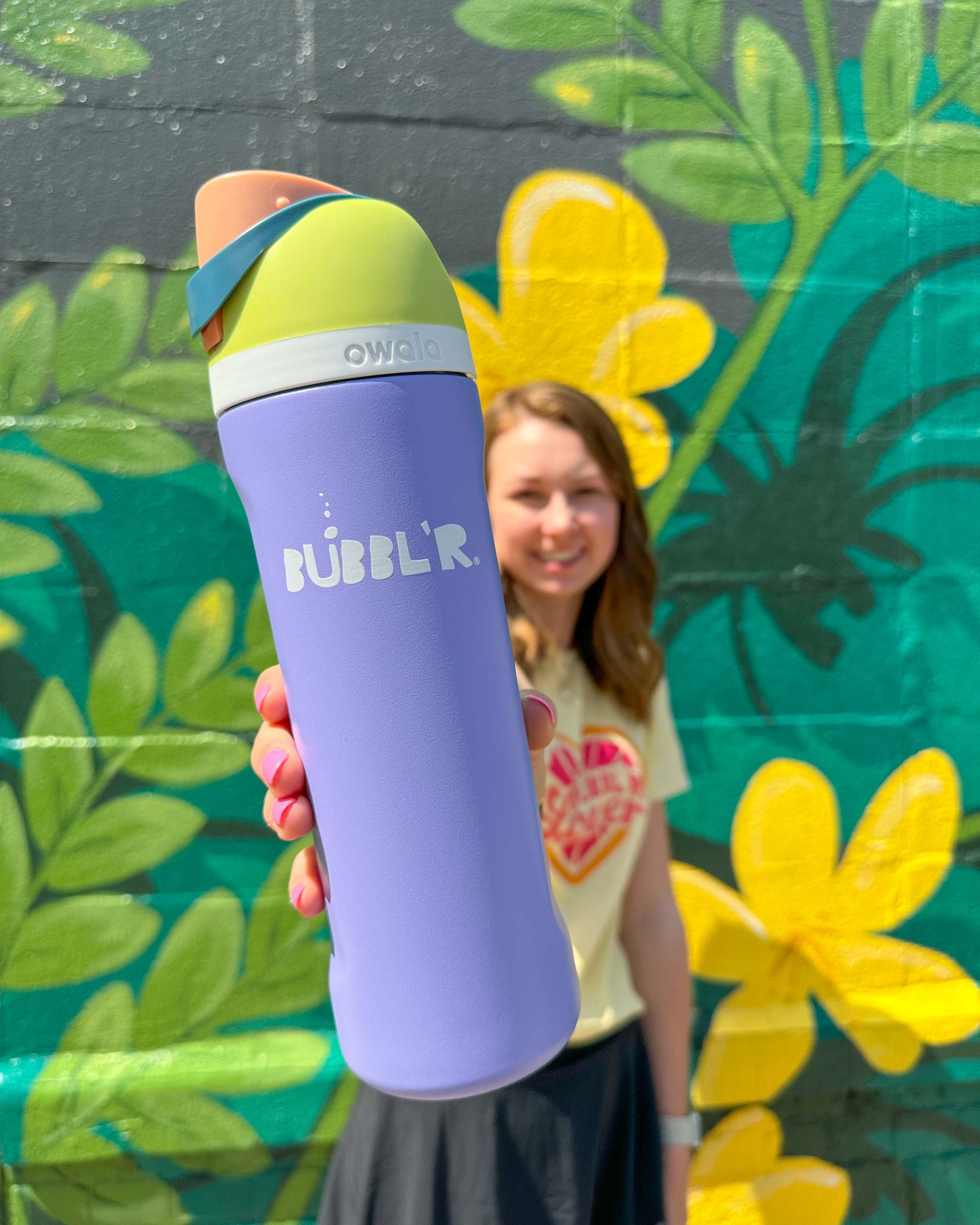 woman holding up purple bottle with white bubbl'r logo